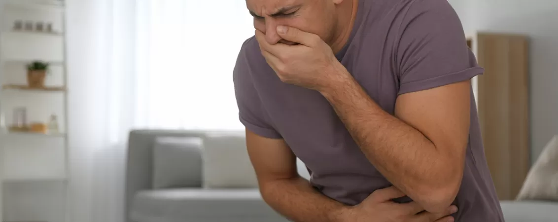Barbat care isi acopera gura si tine mana pe stomac din cauza gretii si durerii