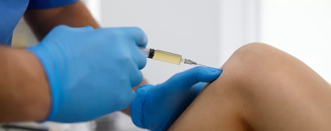 Medic administreaza o injectie cu plasma imbogatita in genunchiul pacientului
