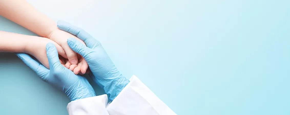 Medic pediatru ține de mână un copil