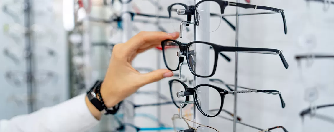 Ochelari de vedere expusi pe raft intr-un magazin de optica