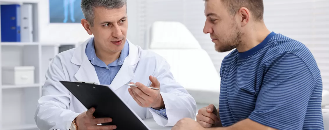 Urolog explica pacientului rezultatele consultului folosind o planseta medicala