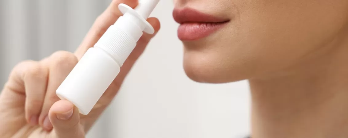 Femeie foloseste un spray nazal pentru ameliorarea congestiei nazale