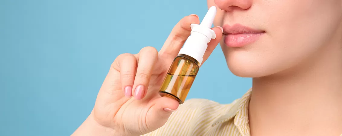 Femeie foloseste un spray nazal pentru ameliorarea congestiei nazale