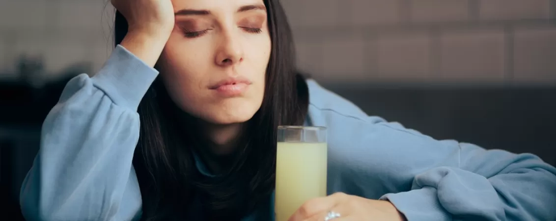 Femeie obosita consuma o bautura efervescenta cu suplimente de calciu si minerale