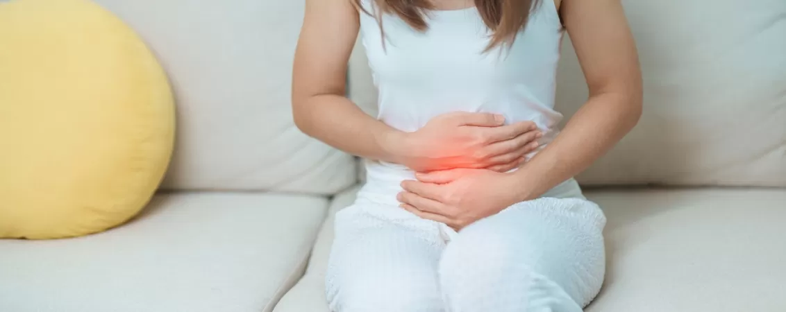Femeie resimte dureri abdominale si isi tine stomacul din cauza disconfortului