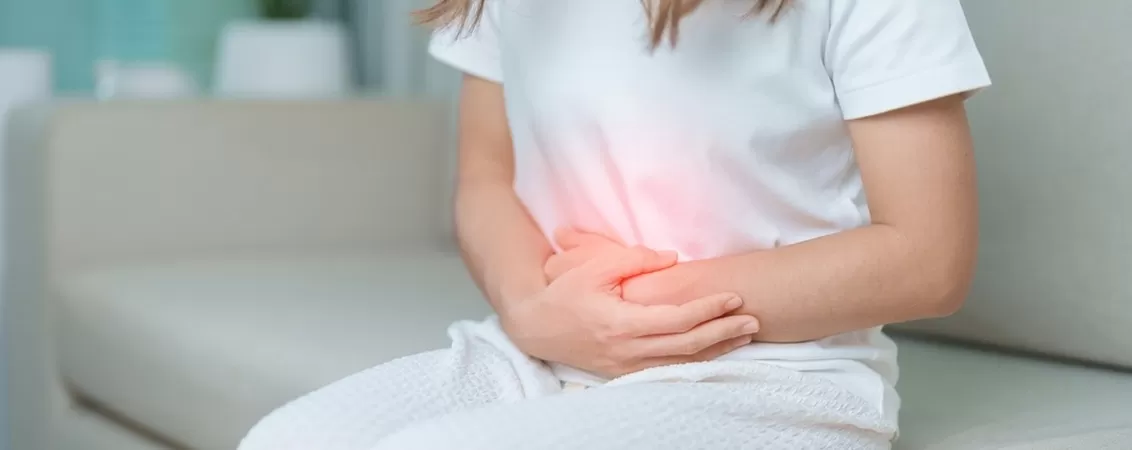Femeie resimte dureri abdominale si isi tine stomacul din cauza disconfortului
