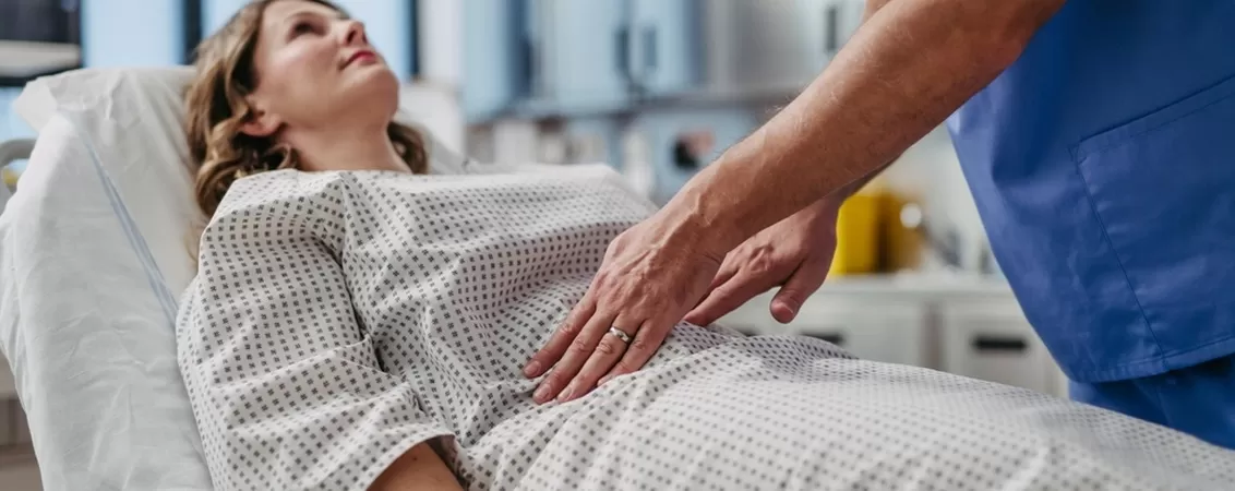 Medic palpeaza abdomenul pacientei pentru evaluarea disconfortului abdominal