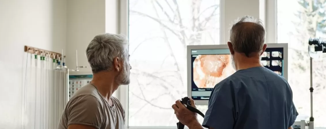 Un medic ii explica pacientului rezultatele colonoscopiei folosind imaginile de pe monitor.