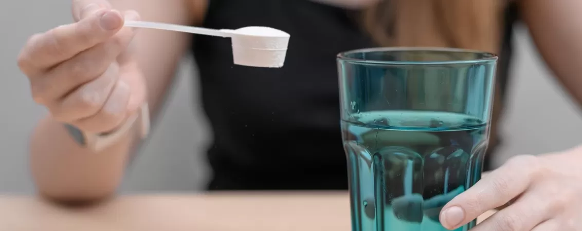 Femeie care bea pudra de colagen dizolvata in apa