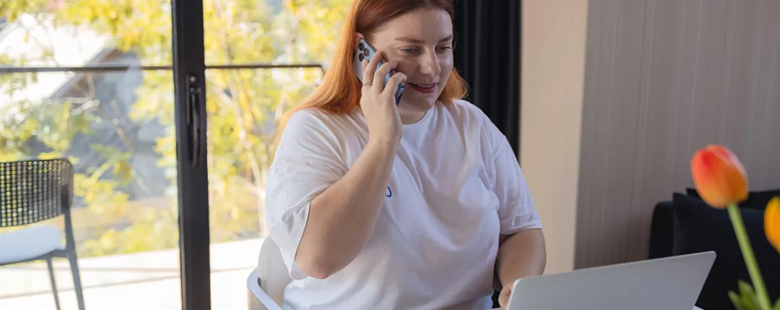Femeie fericita lucreaza la birou folosind laptopul