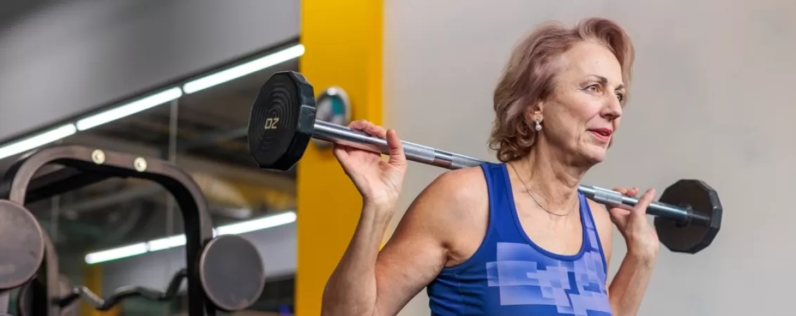 Femeie in varsta face exercitii cu greutati pentru mentinerea masei musculare