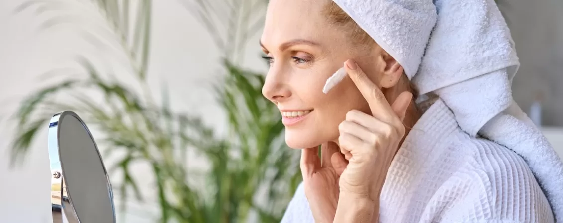 Femeie la menopauza care aplica o crema pe ten