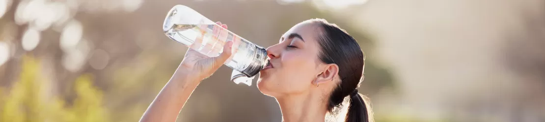 Femeie care se hidrateaza, pentru a evita siadelenita