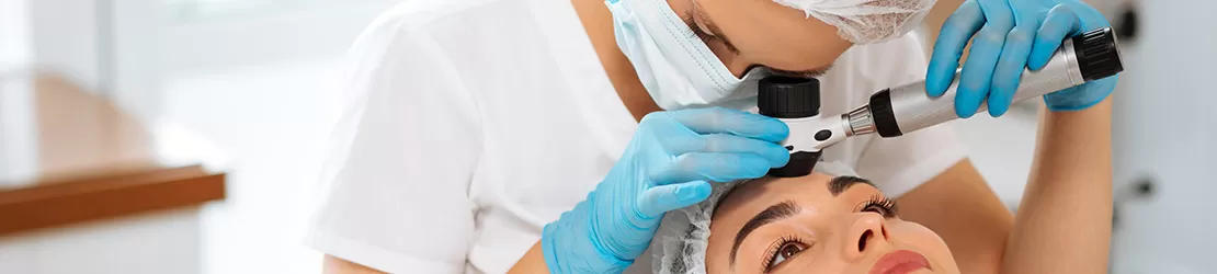 Femeie dermatolog examinand pielea unei paciente in clinica