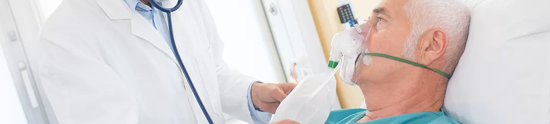 Barbat internat in spital care poarta masca de oxigen si este consultat de medic