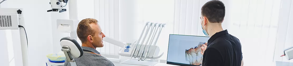 Medic stomatolog discutand cu un pacient intr-un cabinet stomatologic