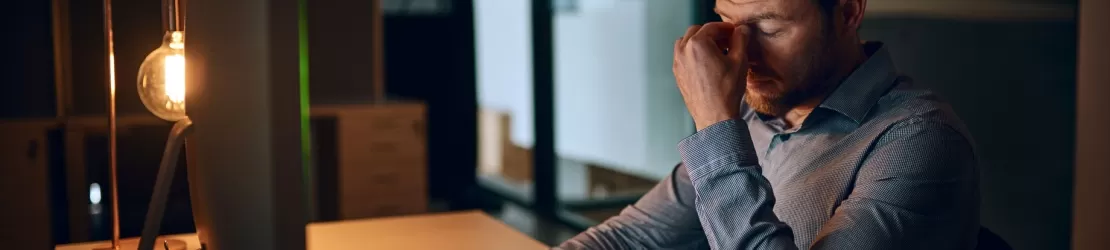 Barbat obosit care sta la birou si lucreaza