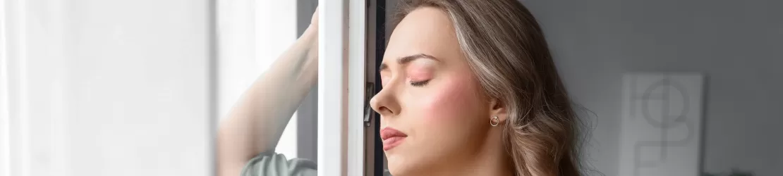 Femeie sufera de hiperventilatie si sta aproape de o fereastra