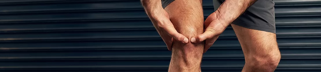 Barbat care isi maseaza genunchiul