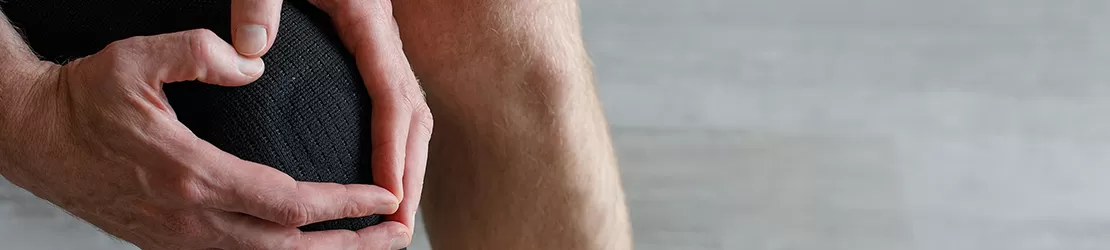 Barbat purtand o orteza neagra pentru genunchi, oferind sustinere articulatiei