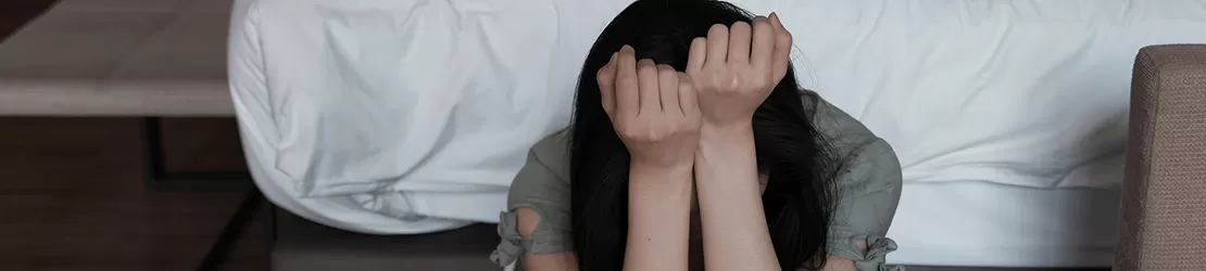 Femeie trista care sta isi tine capul in maini si coatele pe genunchi