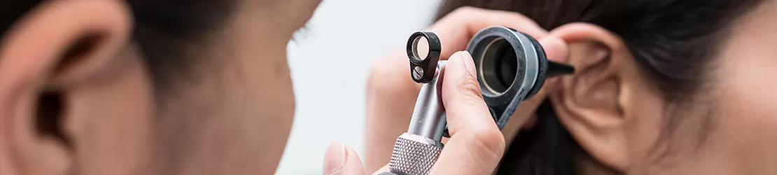 Medic examinand urechea unui pacient in cabinetul medical