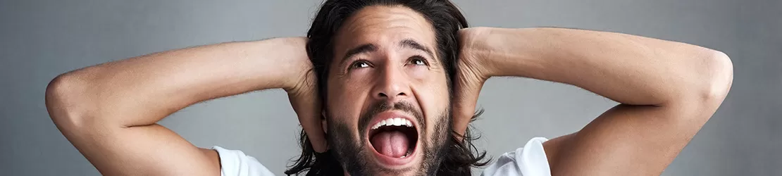 Barbat furios care isi acopera urechile deoarece prezinta o sensibilitate ridicata la anumite sunete