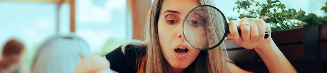 Femeie care analizeaza cu lupa o farfurie cu mancare