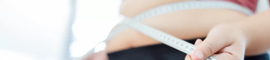 Femeie supraponderala care isi masoara talia