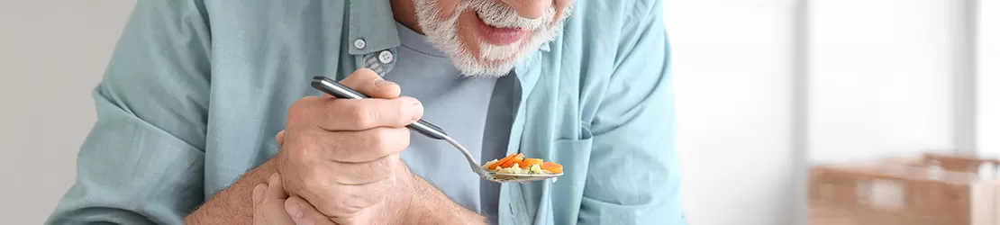 Barbat care sufera de bradikinezie, avand dificultati in a manca din cauza tremurului