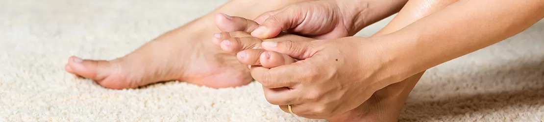 Femeie care isi maseaza picioarele pentru a calma senzatia de furnicaturi in picioare