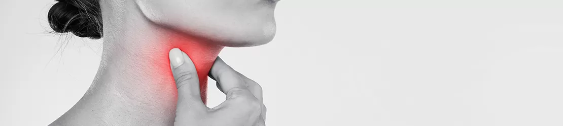 Femeie din profil care isi atinge gatul dureros, semn al unui puroi in gat sau amigdalite.