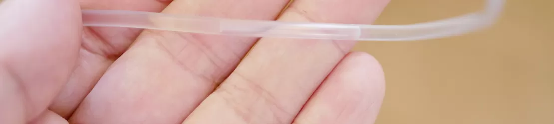 Mana unei asistente care tine un fir de perfuzie in palma pentru a verifica daca este aer in perfuzie