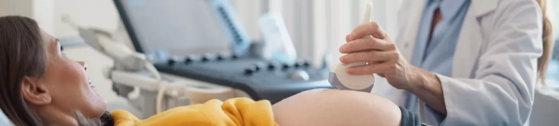 Femeie insarcinata tanara intinsa pe patul unei clinici in timpul consultatiei medicale