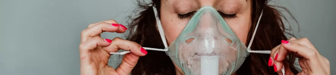 Femeie care foloseste o masca de oxigen pentru a putea respira mai bine