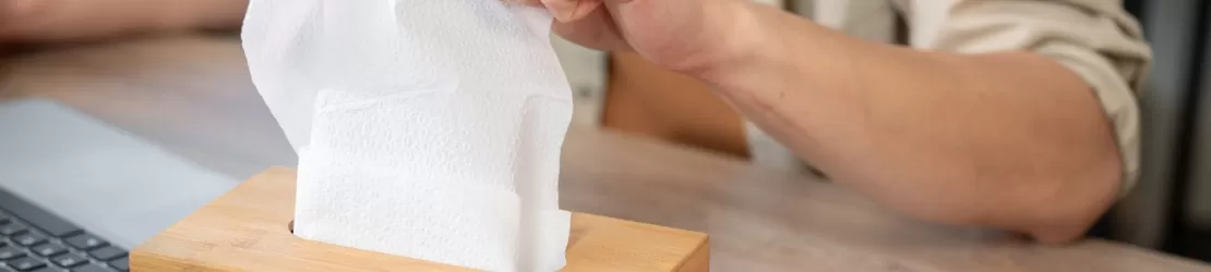 Prim-plan cu un barbat care intinde mana spre un servetel dintr-o cutie de lemn