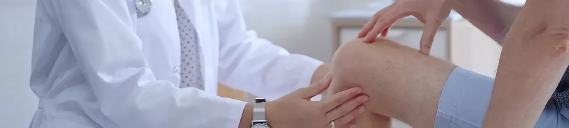 Doctor care verifica genunchiul unui pacient pentru a oferi diagnostic si recomandari de tratament ortopedic