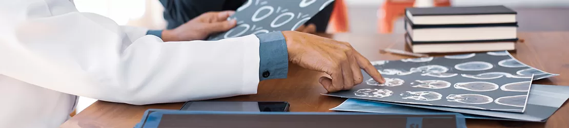 Doctor analizand imagini cu radiografii ale craniului si creierului, evidentiind procesul de analiza si interpretare a imaginilor pentru stabilirea diagnosticului de cavernom cerebral.