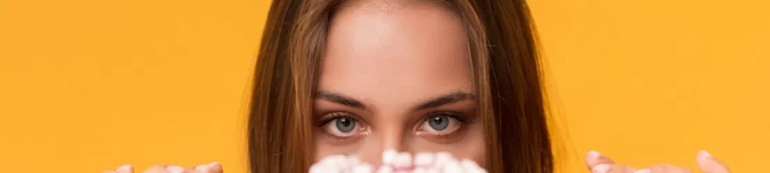 Femeie infometata privind peste masa o gogoasa, ilustrand pofta intensa si pentru anumite alimente.