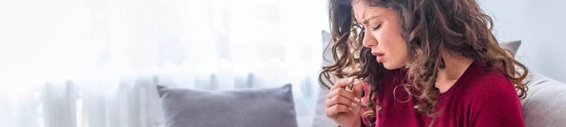 Femeie asezata pe canapea, acoperita cu o patura, pregatita sa administreze o pastila pentru tratarea simptomelor asociate cu afectiunea numita schistosomiaza.