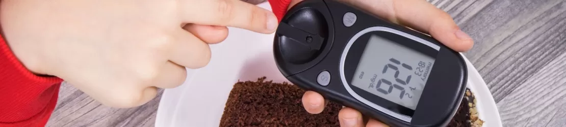 Mana unui copil tinand un glucometru cu rezultat afisat, ilustrand monitorizarea glicemiei si controlul diabetului in randul copiilor.