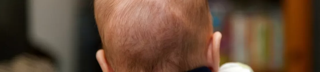 Spatele capului unui bebelus nou-nascut tinut in brate