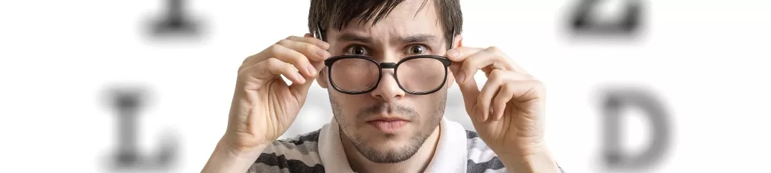 barbat tanar testeaza ochelari cu dioptrii, pentru a corecta hipermetropia