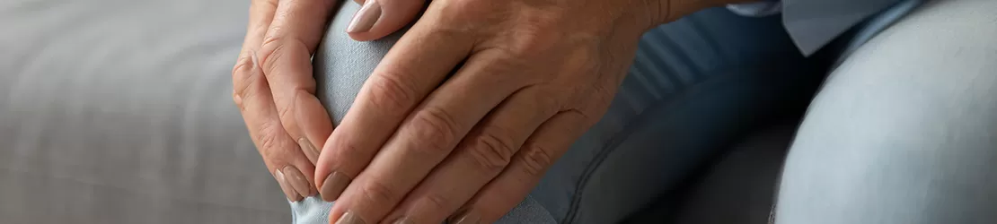 closeup al unei femeie in varsta ce isi maseaza genunchiul