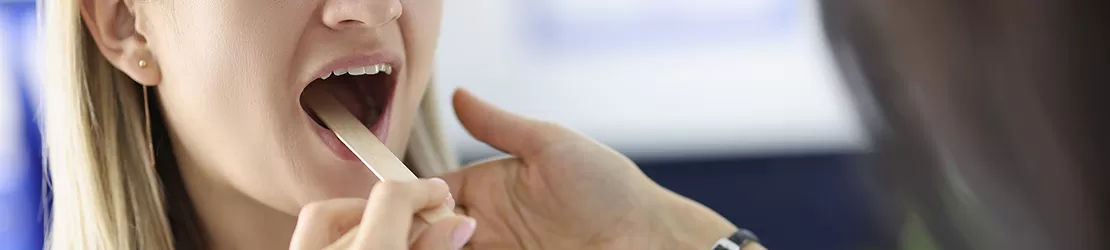 femeie cu spatula in gura in timpul unui control ORL