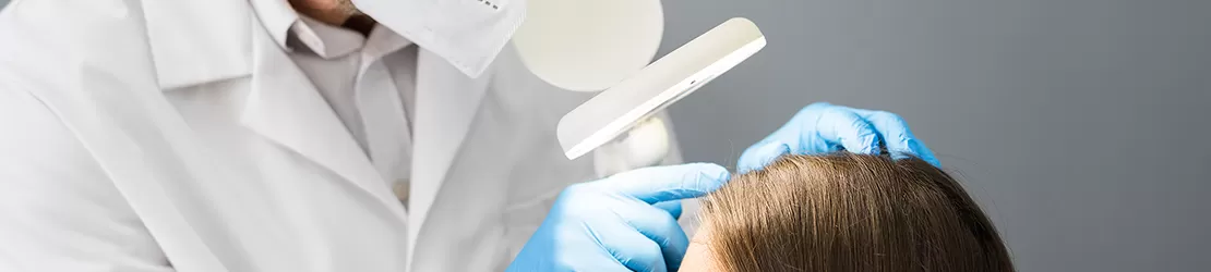 medic dermatolog verifica scalpul unei pacinete pentru semne de tinea