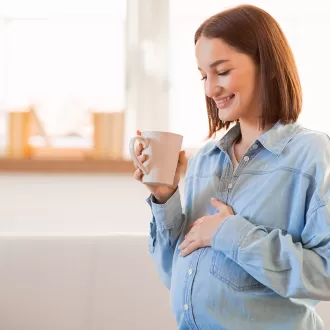 Femeie insarcinata bea o bautura calda in timpul sarcinii