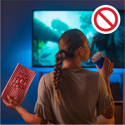 femeie tanara ce mananca si bea suc in fata televizorului