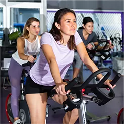 oameni care fac miscare, pedaland pe biciclete de fitness