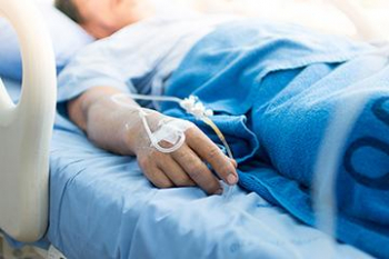 pacient cu perfuzii asezat pe un pat de spital